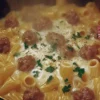 Mezze maniche rigate con crema di fagioli e salsiccia in un piatto gourmet