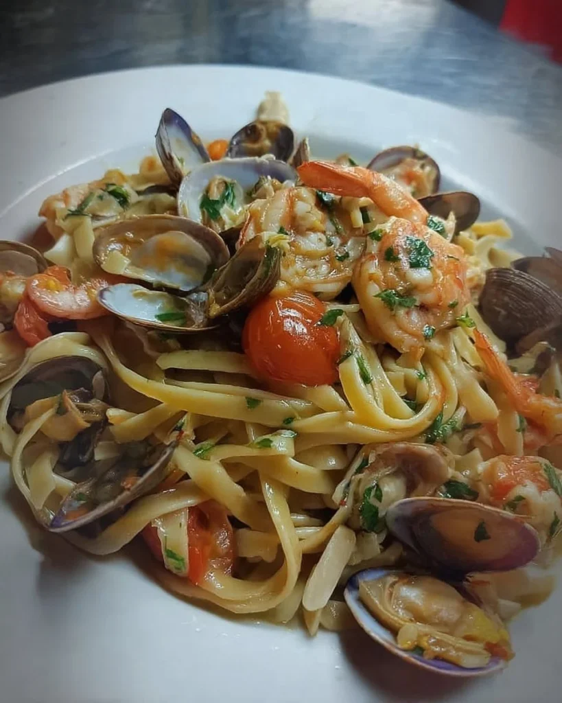 Fettucce con pomodorino, gamberoni, cozze e vongole in un piatto appetitoso