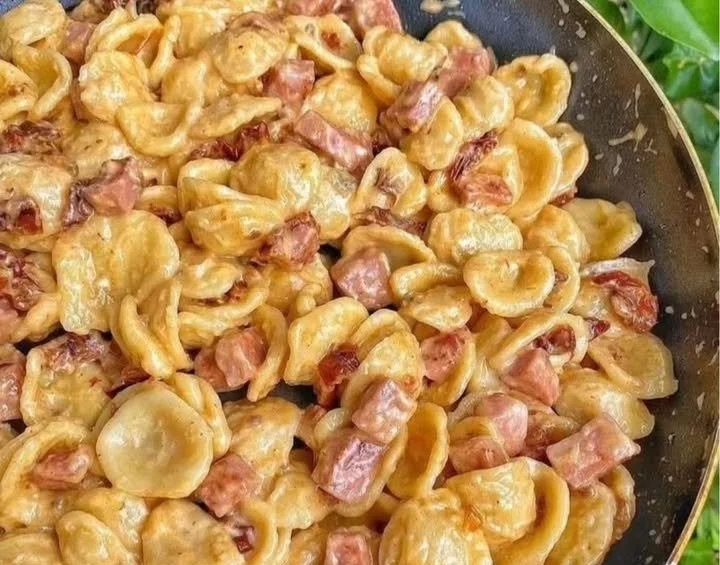 Orecchiette con mortadella e gorgonzola su un piatto rustico.