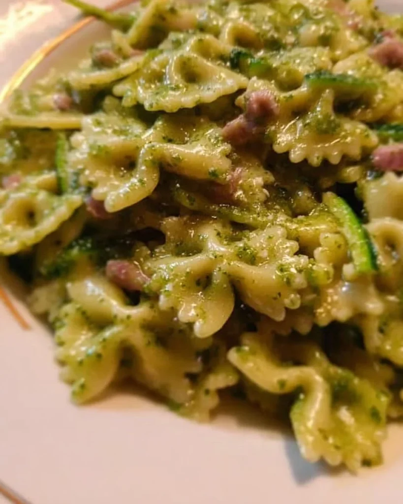 Pasta con pesto alle zucchine servita su un piatto bianco.