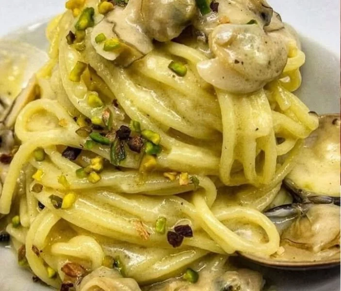 Spaghetti con vongole e pistacchi serviti in un piatto elegante