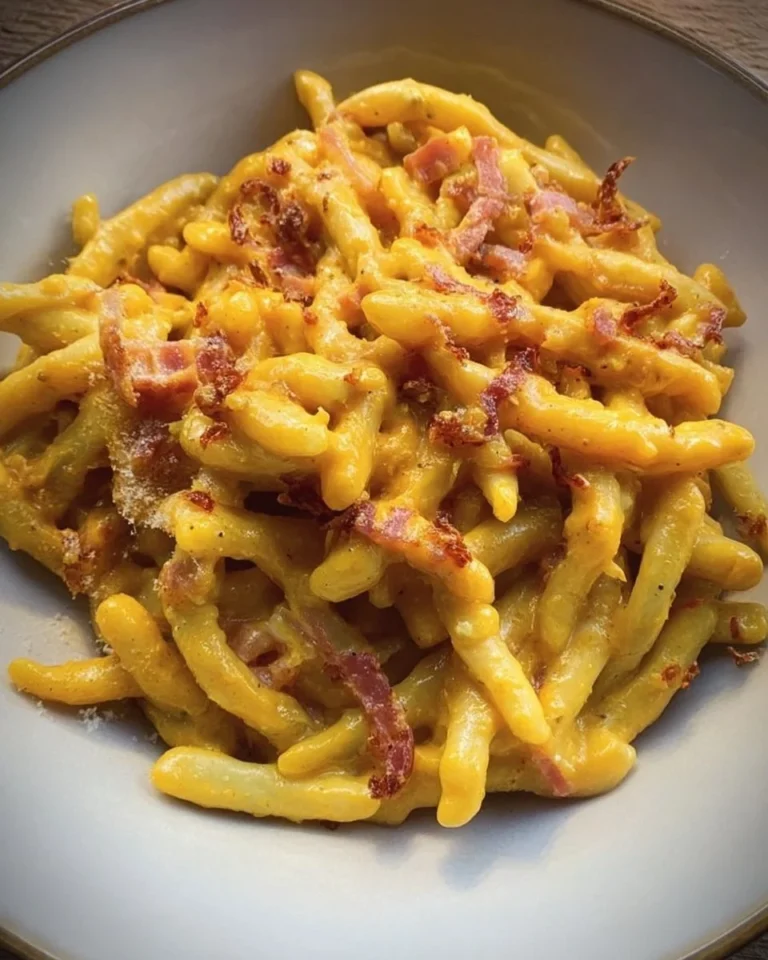 Strozzapreti cremosi con speck, zafferano e grana in un piatto gourmet