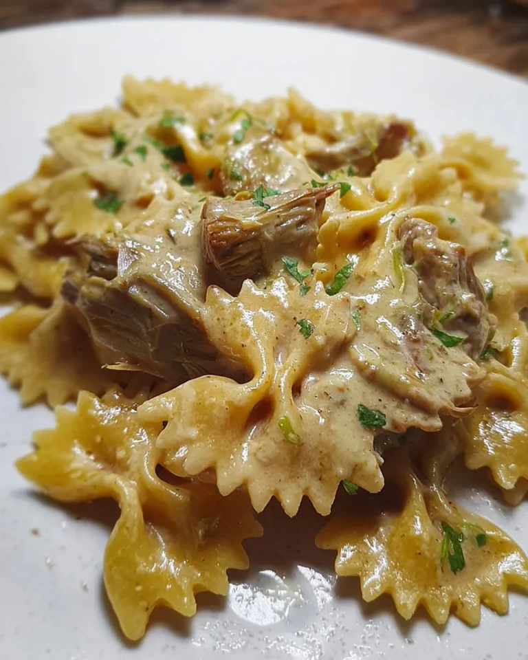 Farfalle con crema di carciofi e cuori trifolati servite in un piatto.