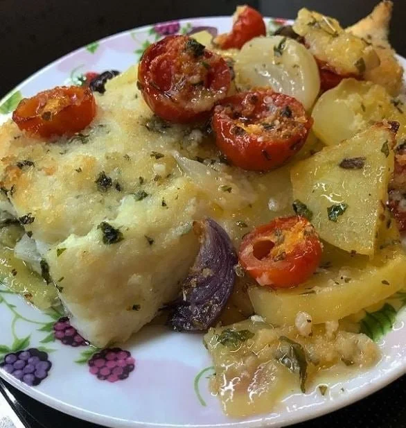 Baccalà al forno con patate, pomodorini e olive servito su un piatto