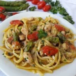 Bavette con pesce spada, asparagi e pomodorini servite in un piatto