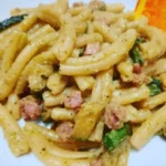 Casarecce con crema di zucchine, pancetta croccante e Philadelphia in un piatto appetitoso