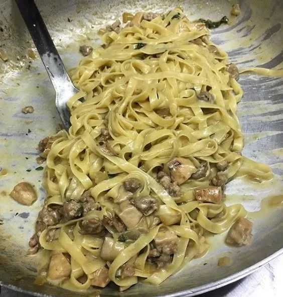 Piatto di fettuccine con funghi porcini e salsiccia, ricetta italiana