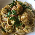 Fettuccine gamberetti con pesto e pomodoro fresco su un piatto gourmet.