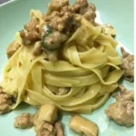 Fettuccine con funghi porcini e salsiccia in un piatto gustoso e invitante.