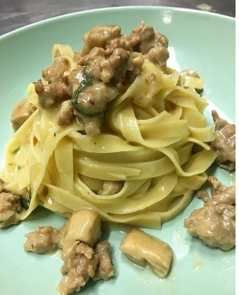 Fettuccine con funghi porcini e salsiccia in un piatto gustoso e invitante.