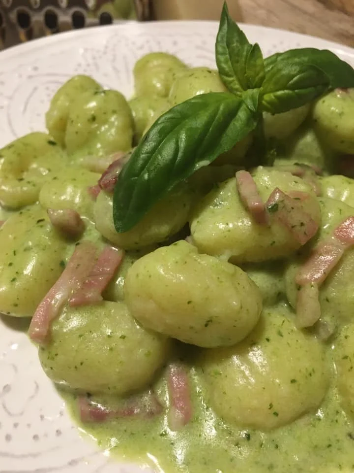 Gnocchi di patate con crema di Speck, Robiola e Pesto serviti in un piatto gourmet.