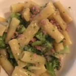 Pasta broccoli e salsiccia servita su un piatto bianco con una spolverata di pepe