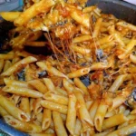 Pasta con Melanzane Fritte e Provola Affumicata servita in un piatto elegante