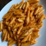 Penne alla Vodka con salsa cremosa e pomodoro fresco in un piatto decorato