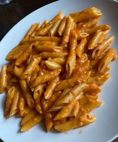 Penne alla Vodka con salsa cremosa e pomodoro fresco in un piatto decorato