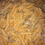 Piatto di pennette ai funghi servito con una spruzzata di prezzemolo fresco