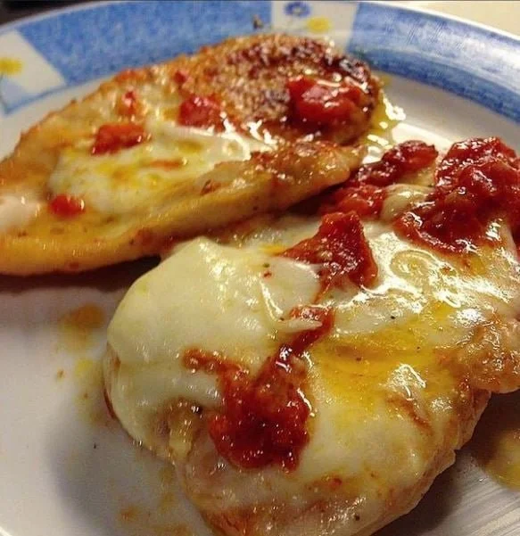 Petti di pollo alla pizzaiola con pomodorini e mozzarella su un piatto