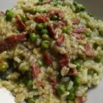 Risotto con speck, piselli e curry in un piatto elegante