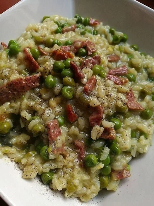 Risotto con speck, piselli e curry in un piatto elegante