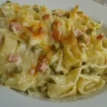 Tagliatelle al forno con prosciutto cotto e piselli serviti su un piatto