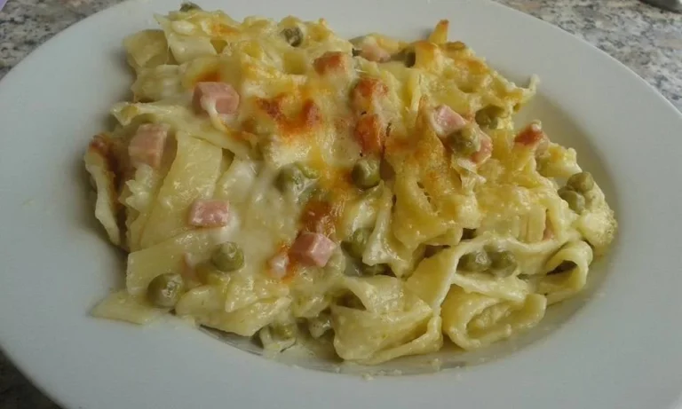 Tagliatelle al forno con prosciutto cotto e piselli in una teglia