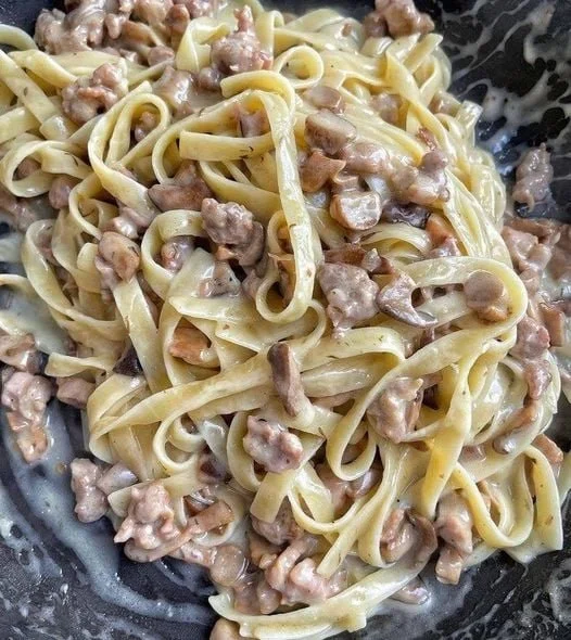 Tagliatelle con funghi porcini e salsiccia in un piatto gourmet