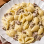 Piatto di conchiglie con crema di patate e salsiccia