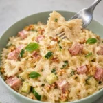 Farfalle cremose con zucchine, prosciutto, Philadelphia e noci in un piatto appetitoso.