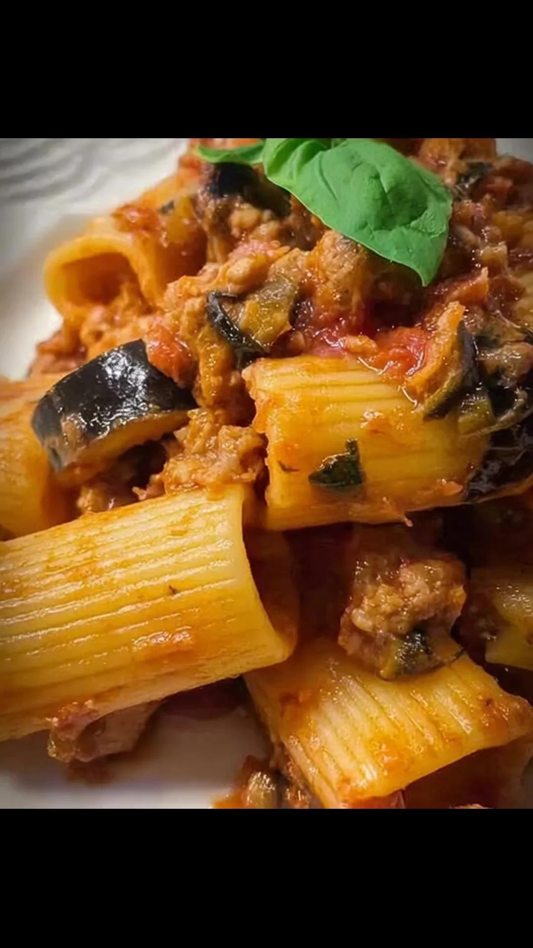 Paccheri con melanzane e salsiccia conditi in un piatto appetitoso