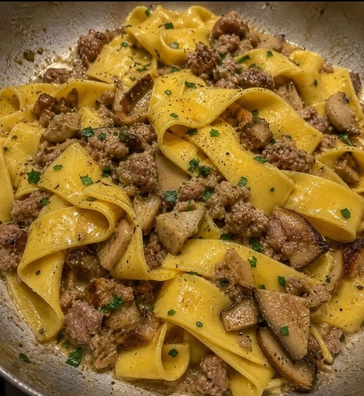 Pappardelle con funghi porcini e salsiccia su un piatto elegante