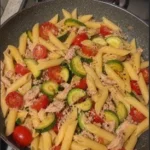 Pasta con tonno, zucchine e pomodorini in un delizioso piatto estivo.