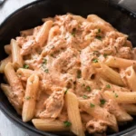 Penne al baffo con tonno pronto da servire su un piatto decorato