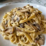 Tagliatelle con crema di parmigiano e funghi porcini serviti in un piatto elegante.