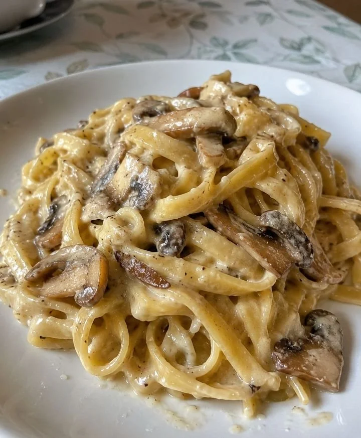 Tagliatelle con crema di parmigiano e funghi porcini serviti in un piatto elegante.