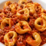 Tortellini ripieni di carne con salsiccia al sugo serviti in un piatto